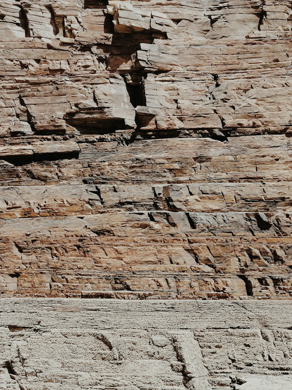 person in brown jacket and black pants standing on brown rock formation during daytime