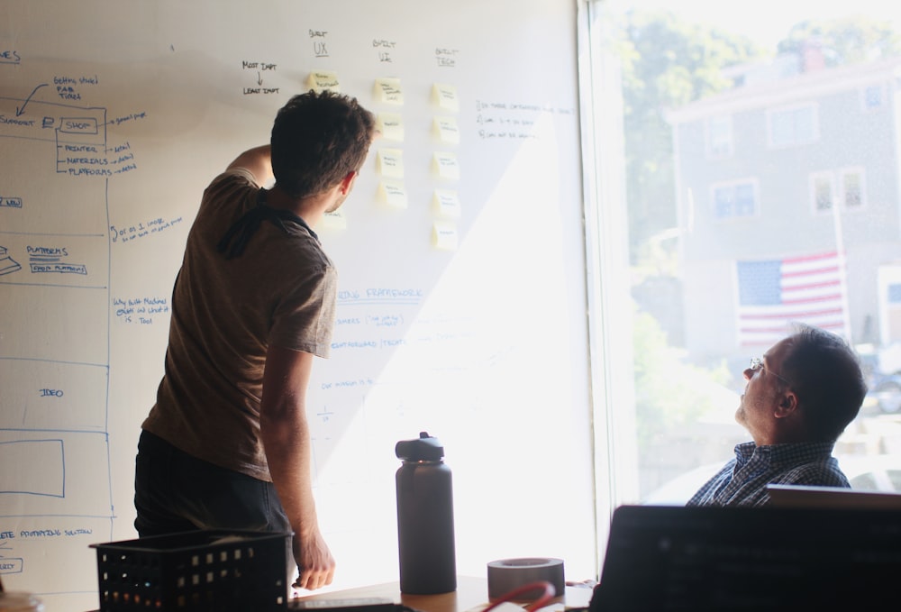 man in gray crew neck t-shirt standing near whiteboard