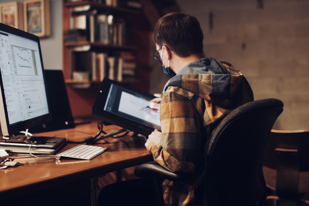 man in brown and white plaid dress shirt sitting on black office rolling chair