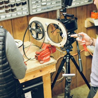 person holding black camera on brown wooden table