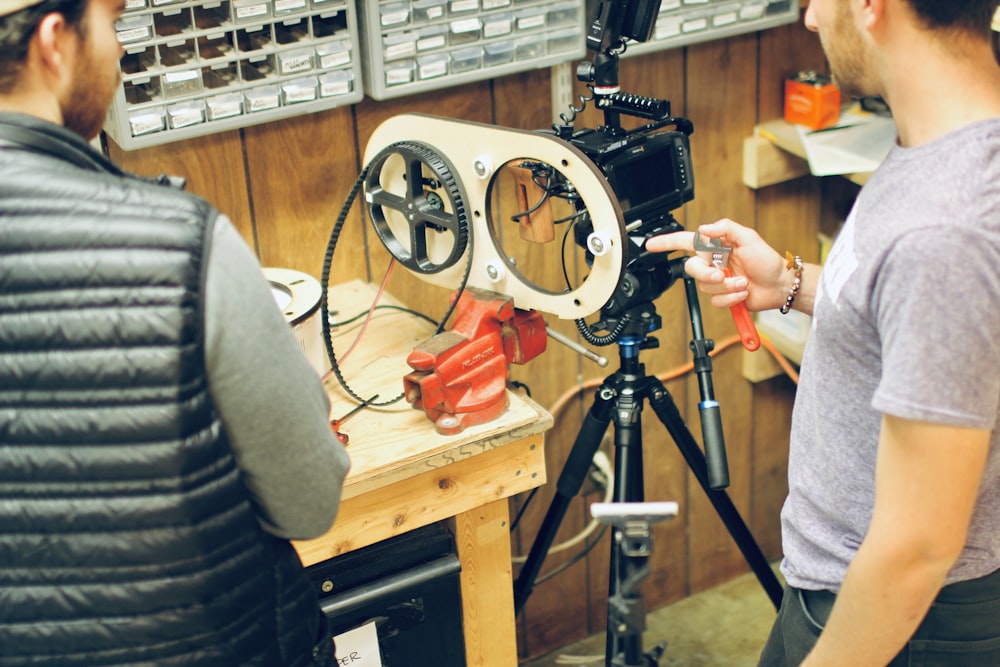 person holding black camera on brown wooden table