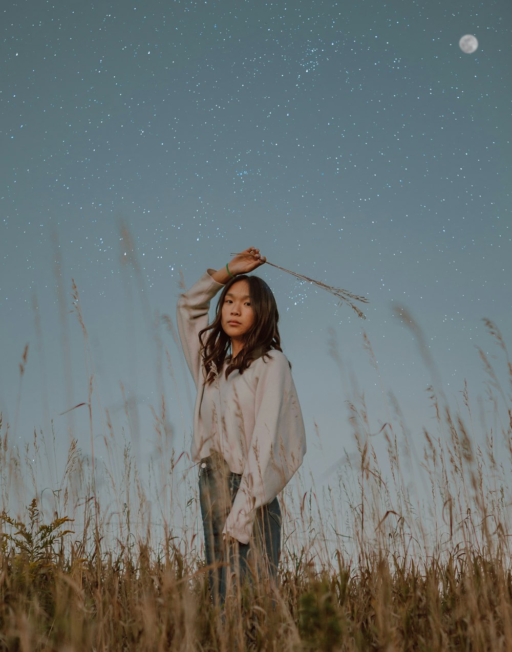 woman in white coat standing on grass field under blue sky during daytime