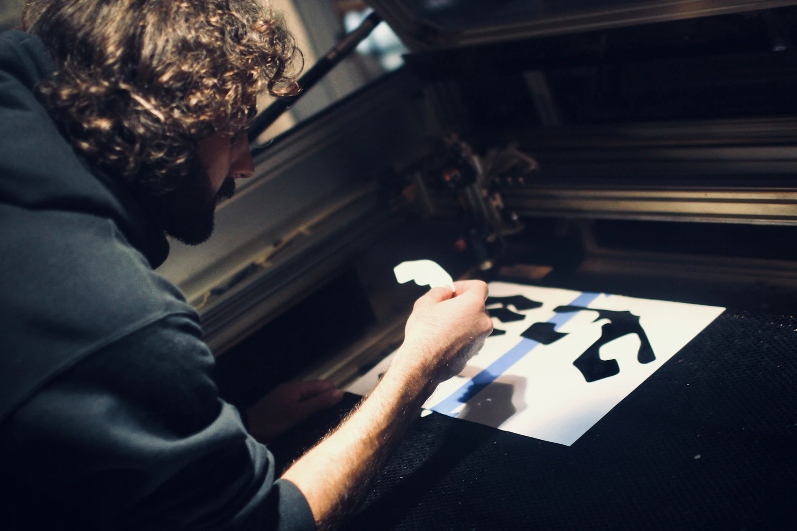 Operator removing laser-cut pieces from a honeycomb laser cutter bed
