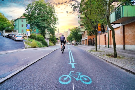 man in black jacket riding bicycle on road during daytime in Gothenburg Sweden