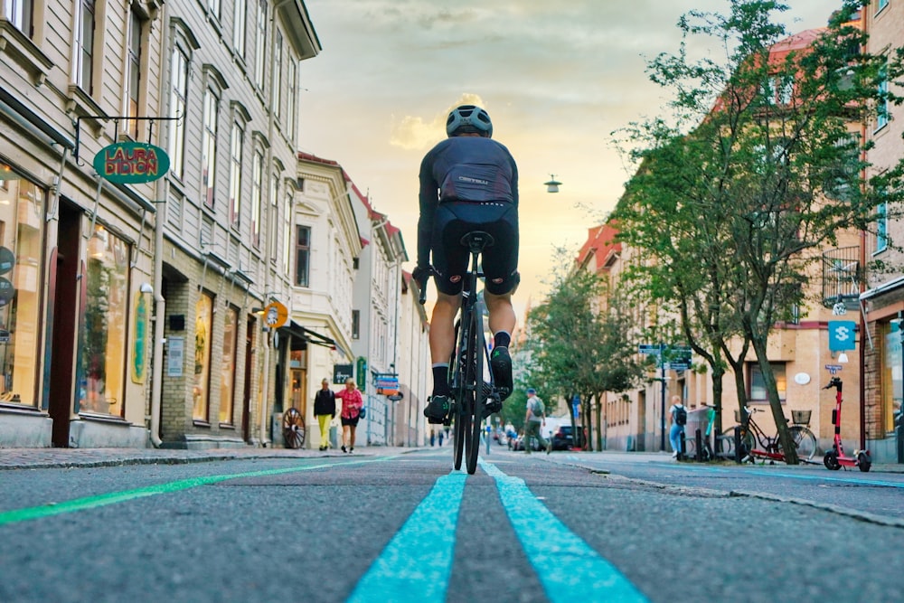 man in black jacket riding bicycle on road during daytime