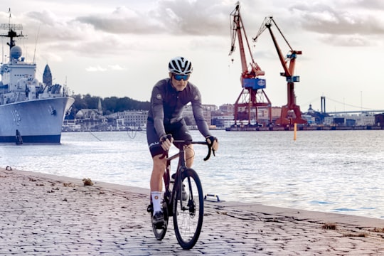 man in black and white bicycle helmet riding bicycle on beach during daytime in Gothenburg Sweden