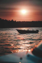 A warm sunset view over the mangroves with a small boat gently floating nearby.
