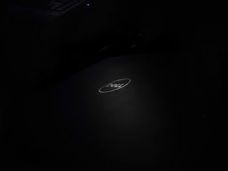 A dark image with a Dell laptop logo centrally placed, featuring a softly illuminated keyboard in the top left corner.