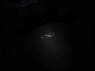 A Dell Inspiron laptop open on a light gray desk with soft natural lighting highlighting its keyboard