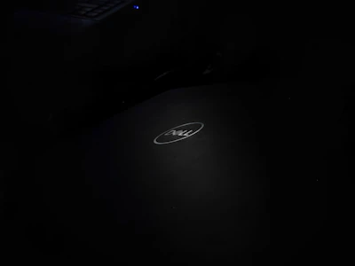 A Dell Inspiron laptop open on a light gray desk with soft natural lighting highlighting its keyboard