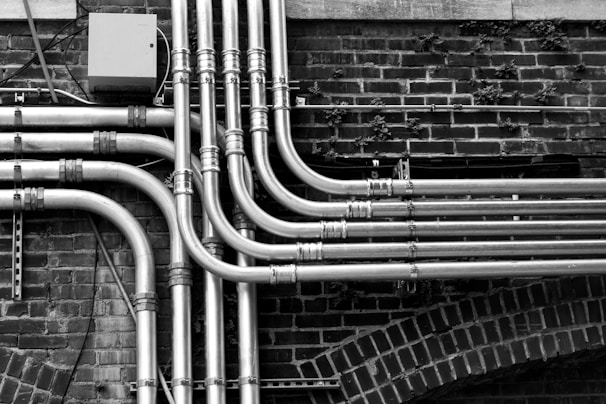 Black and white photo of a crew installing plumbing pipes in a residential basement.