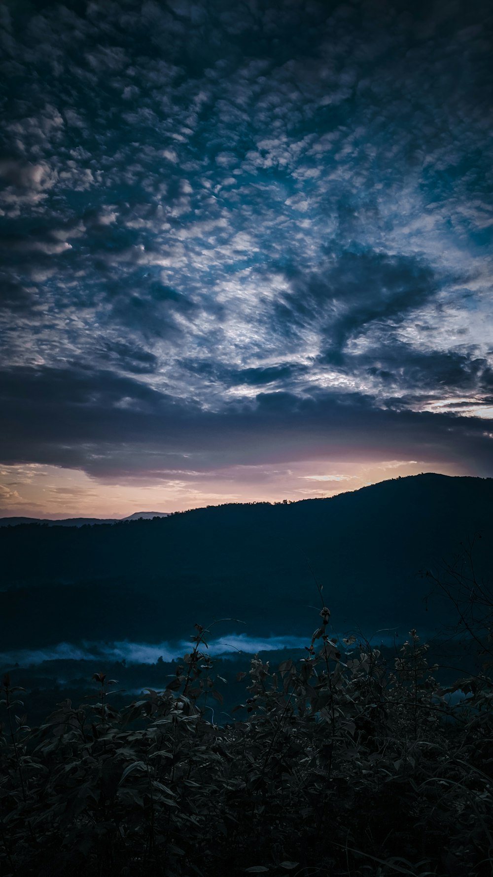 silhouette of mountain under cloudy sky during sunset