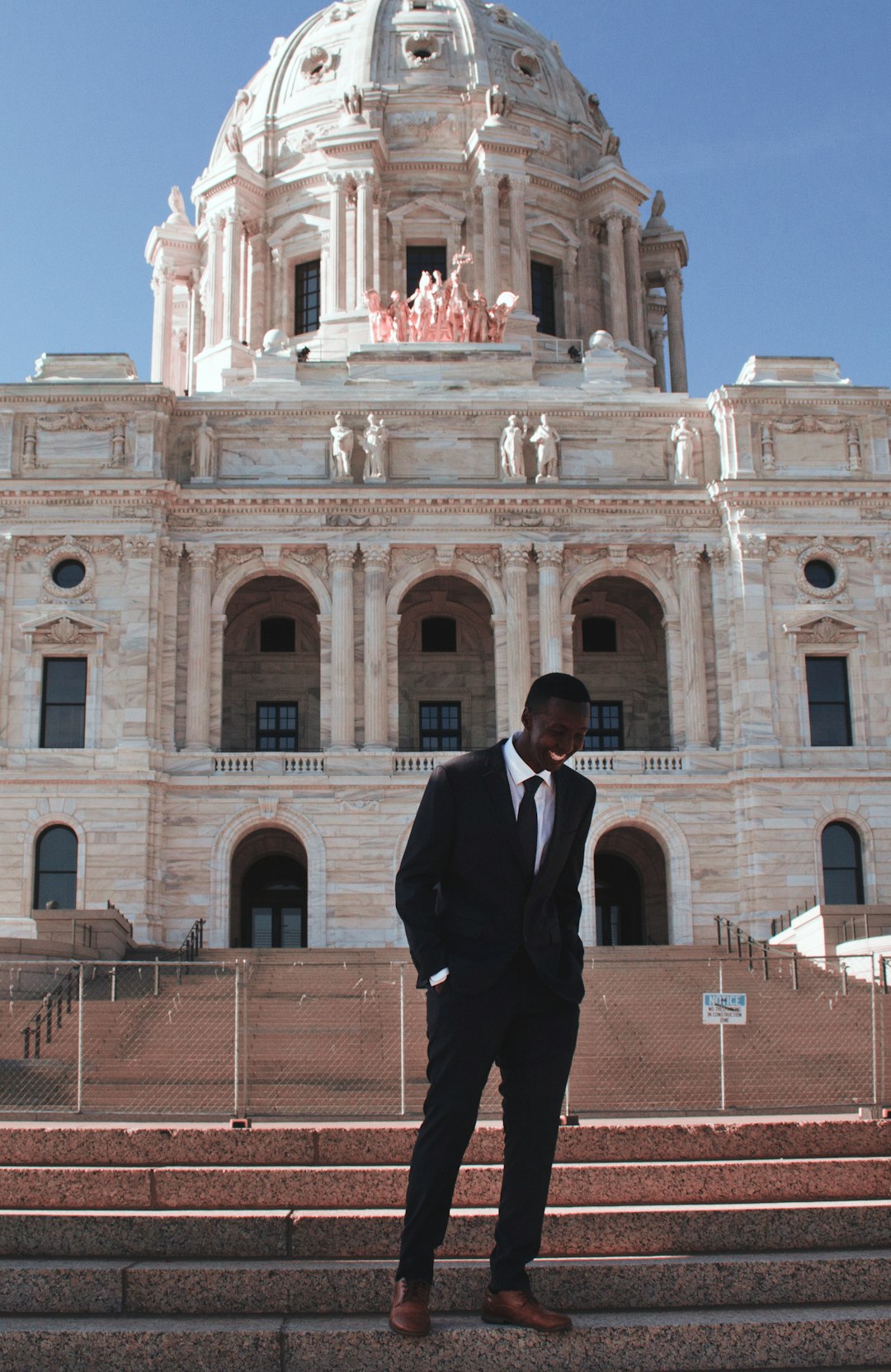 man in black suit standing near beige concrete building during daytime