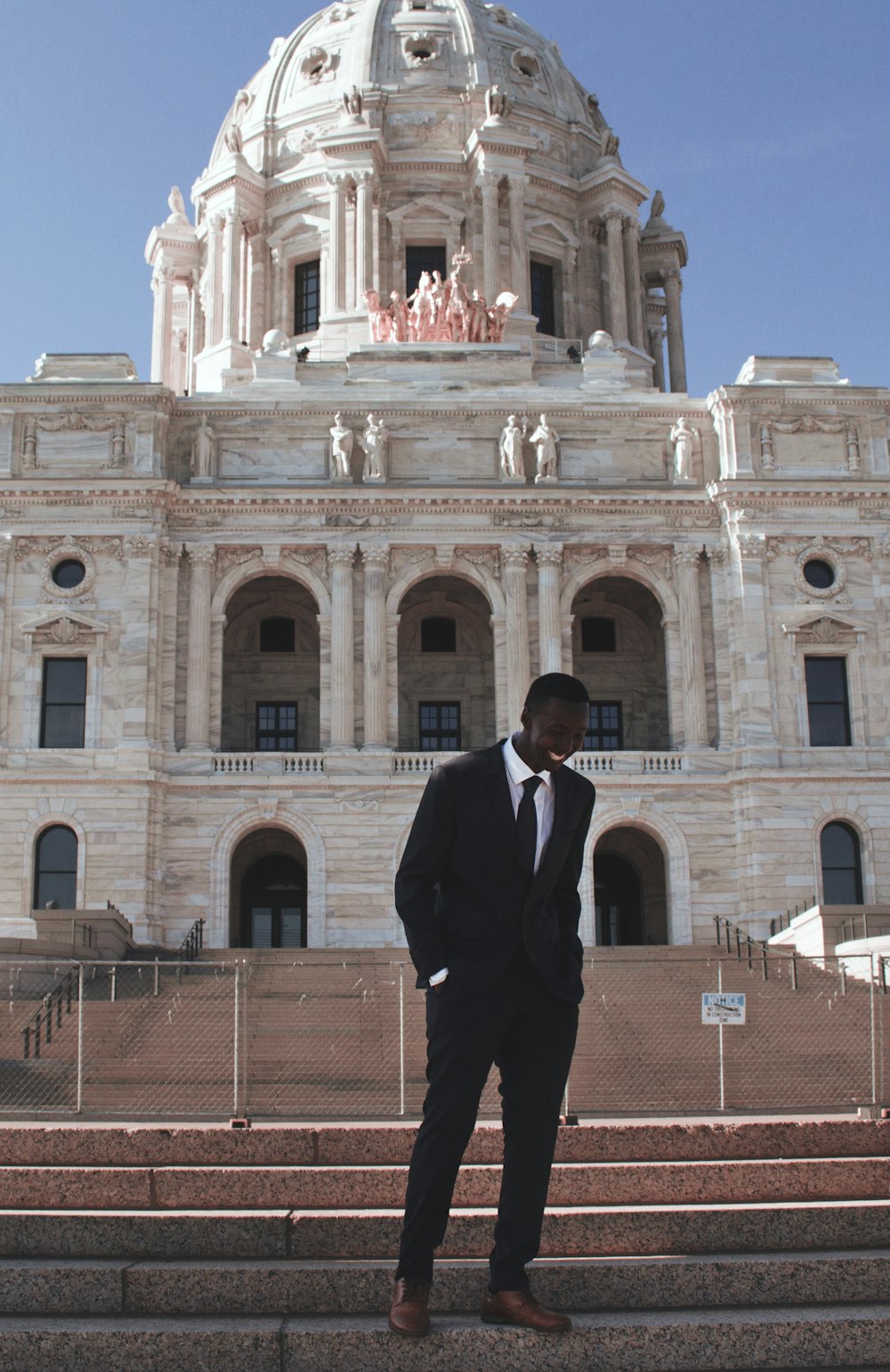 man in black suit standing near beige concrete building during daytime