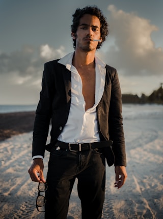 woman in black blazer standing on seashore during daytime