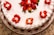 A close-up of a beautifully decorated chocolate cake with fresh strawberries on top, placed on a rustic wooden table.