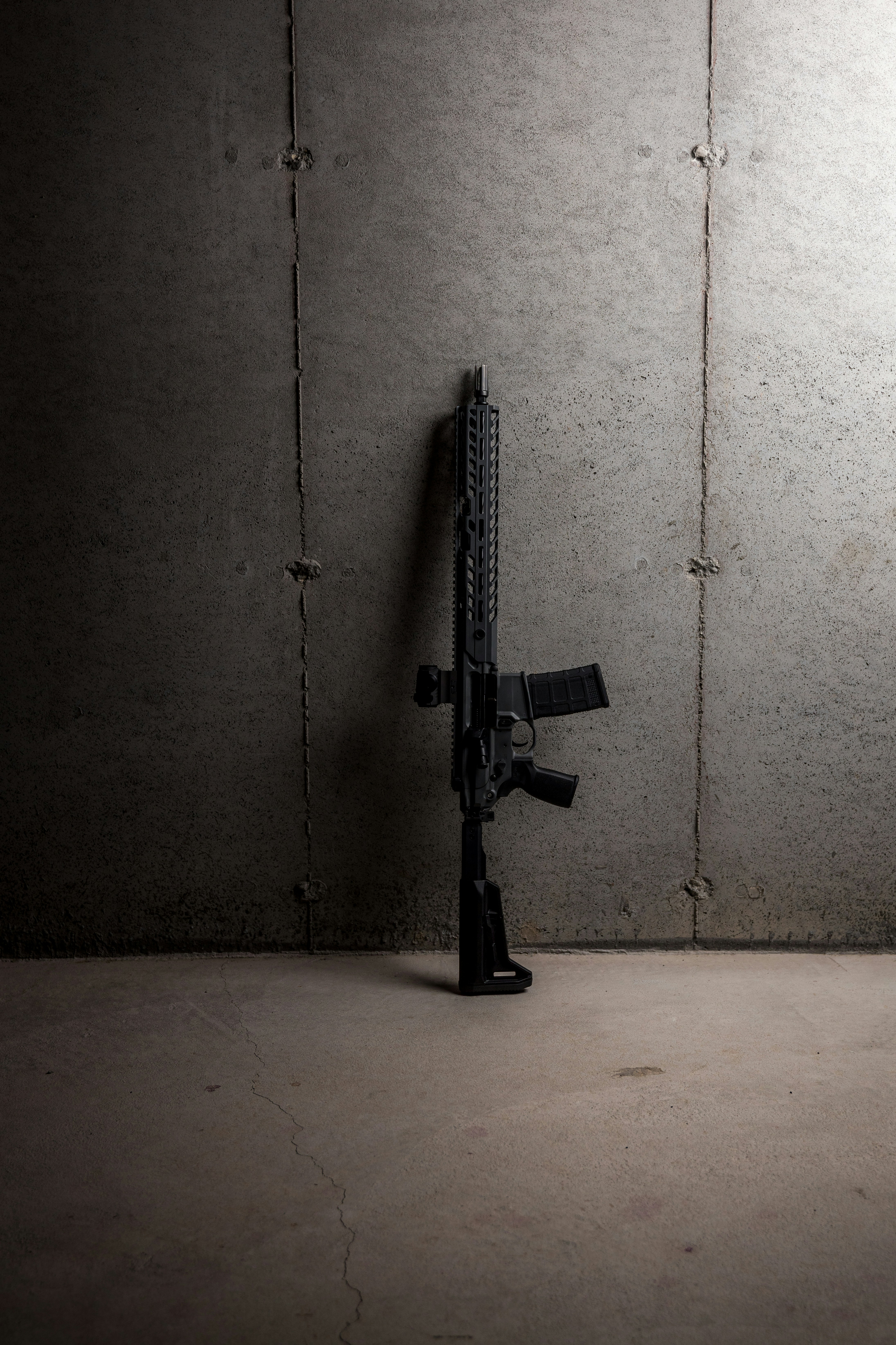 black rifle leaning on white wall