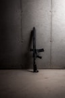 black rifle leaning on white wall