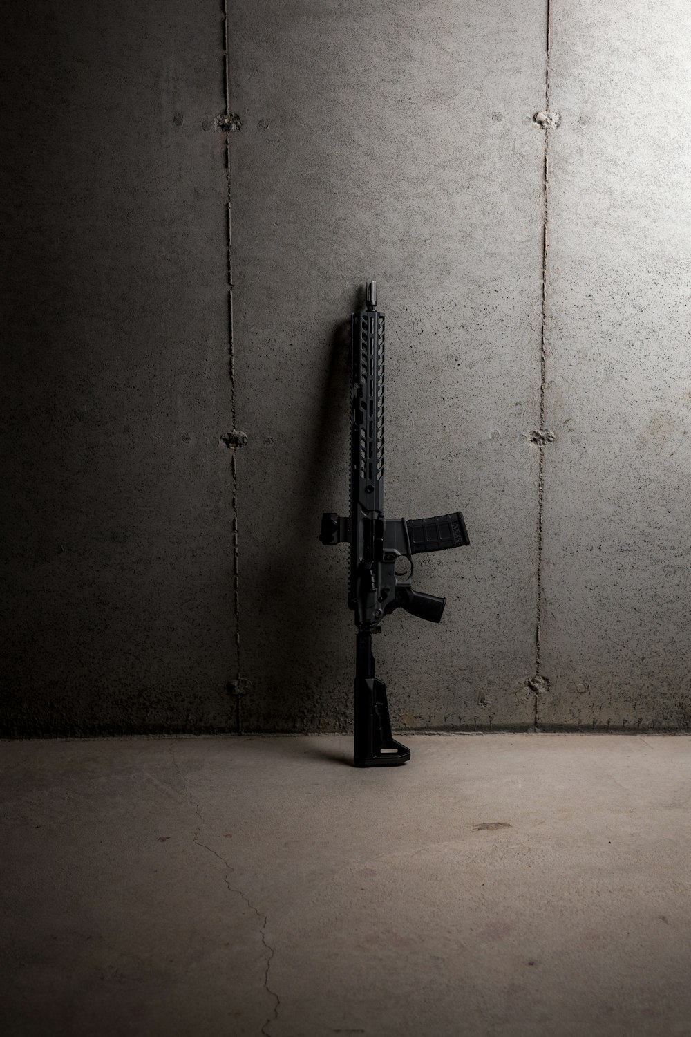 black rifle leaning on white wall