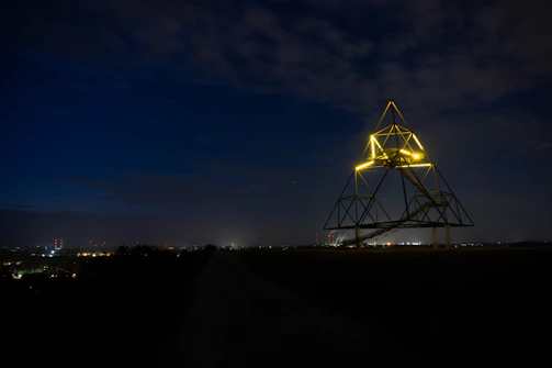 Outdoor triedro iluminado em ponto estratégico da cidade à noite.