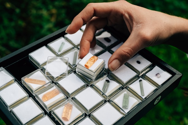 Happy customer holding a small box with a gemstone, smiling warmly in a cozy home setting.