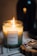 A lit candle labeled 'Forest' with scents of fennel, lemongrass, sandalwood, and mandarin is placed on a surface beside an open matchbox containing blue-tipped matches. The background is softly blurred, contributing to a warm and cozy ambiance.