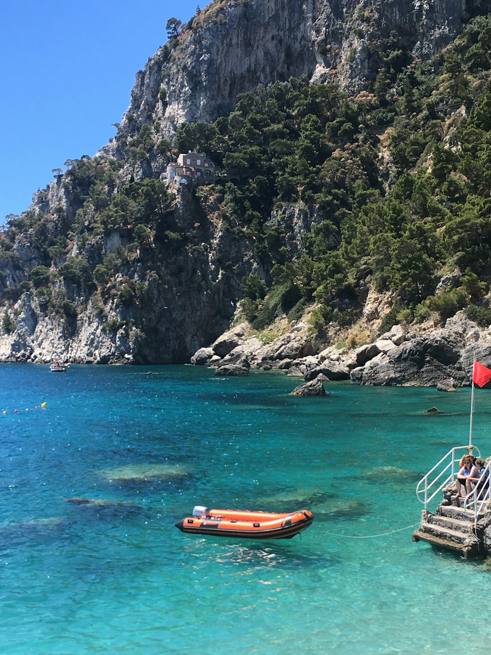 orange and white boat on sea near mountain during daytime