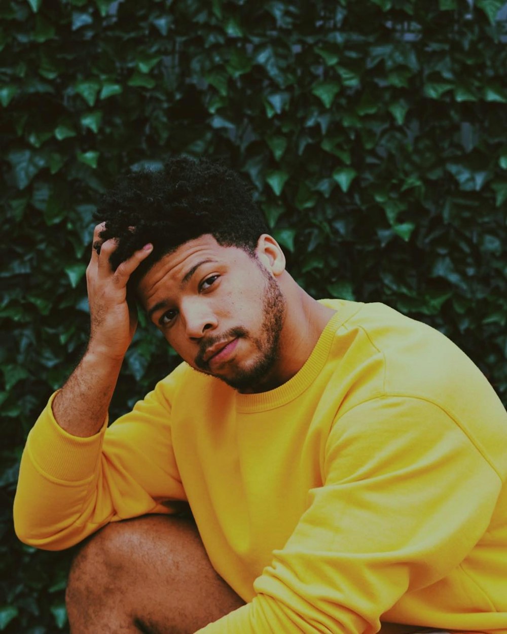 man in yellow crew neck t-shirt sitting on green grass during daytime