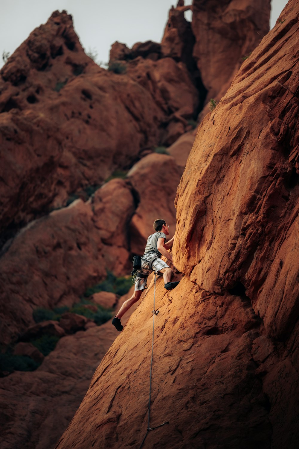 Hombre con camisa blanca escalando la montaña de roca marrón durante el día