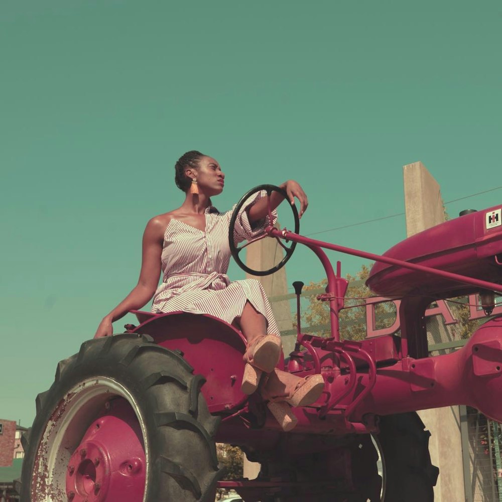 Mujer en camiseta blanca sin mangas montando tractor rojo durante el día