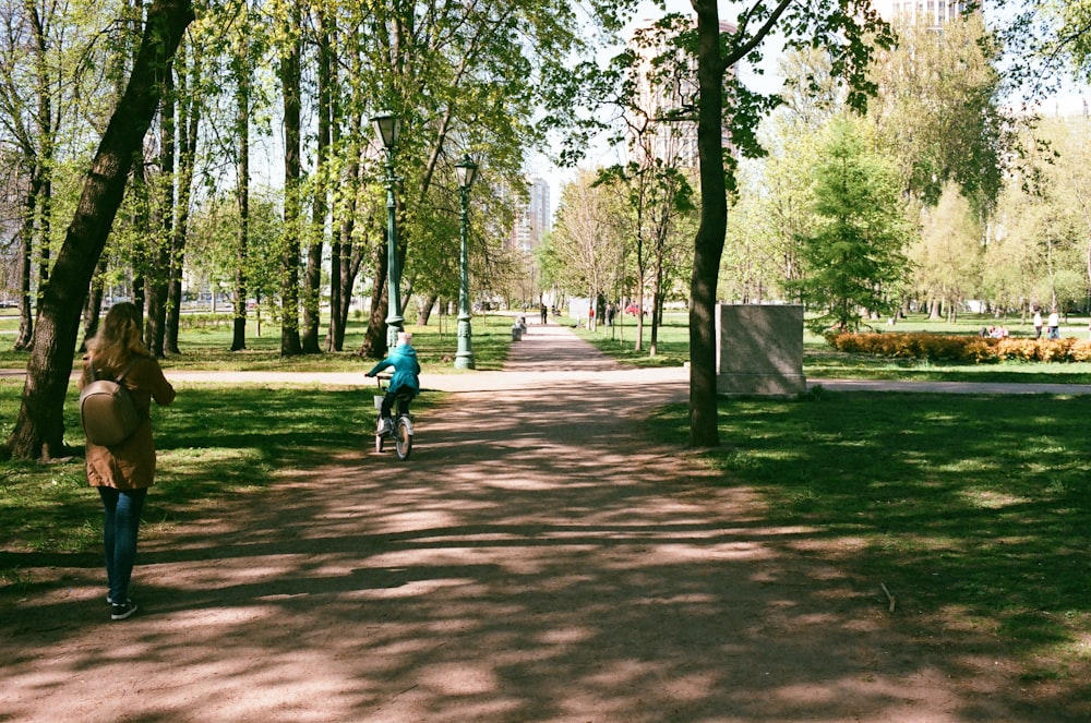 昼間の公園で自転車に乗る青いジャケットの男