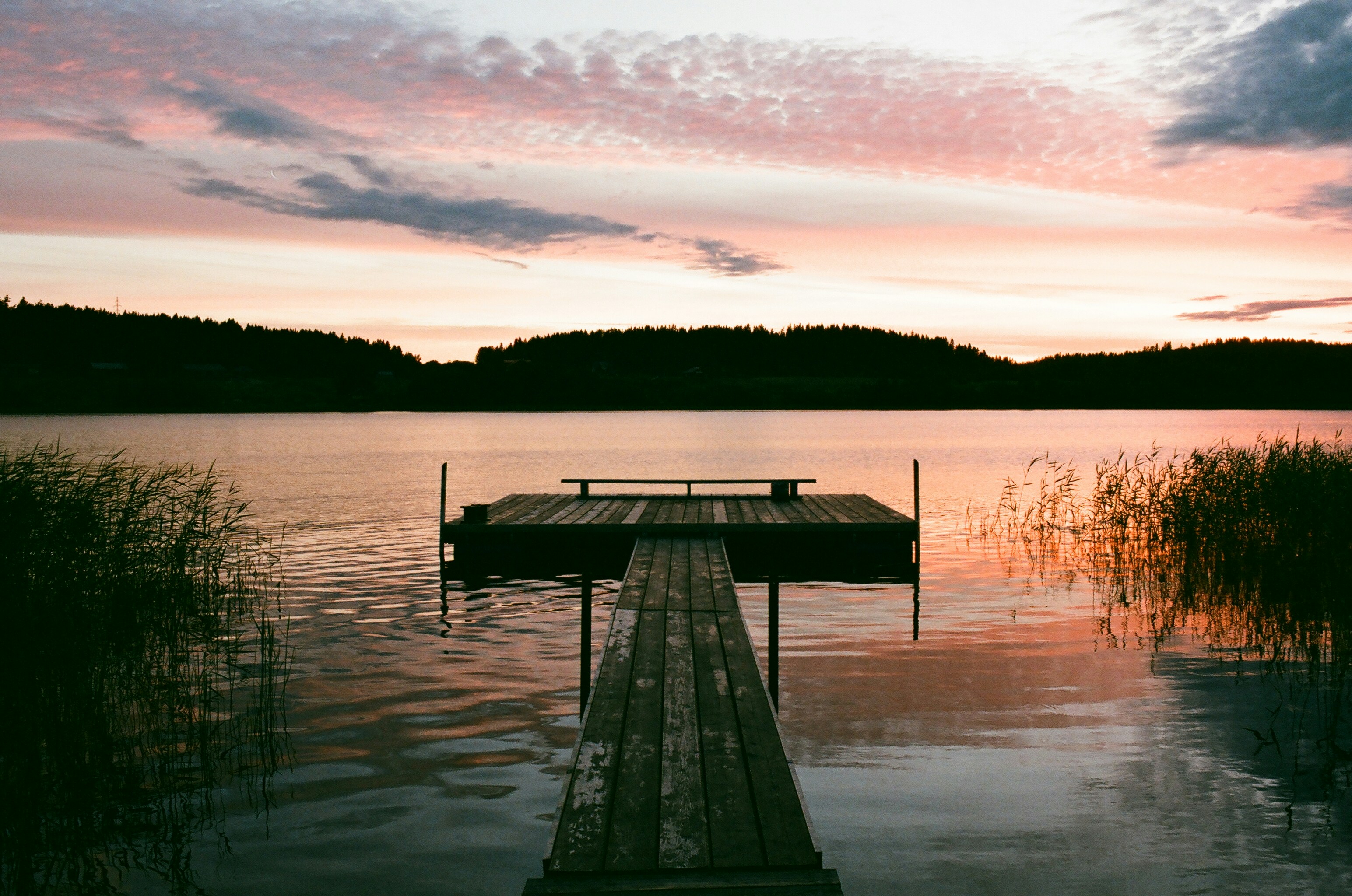 brown wooden dock on lake during sunset