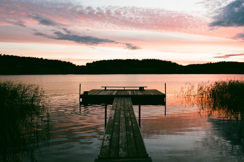 Quai en bois brun sur le lac au coucher du soleil