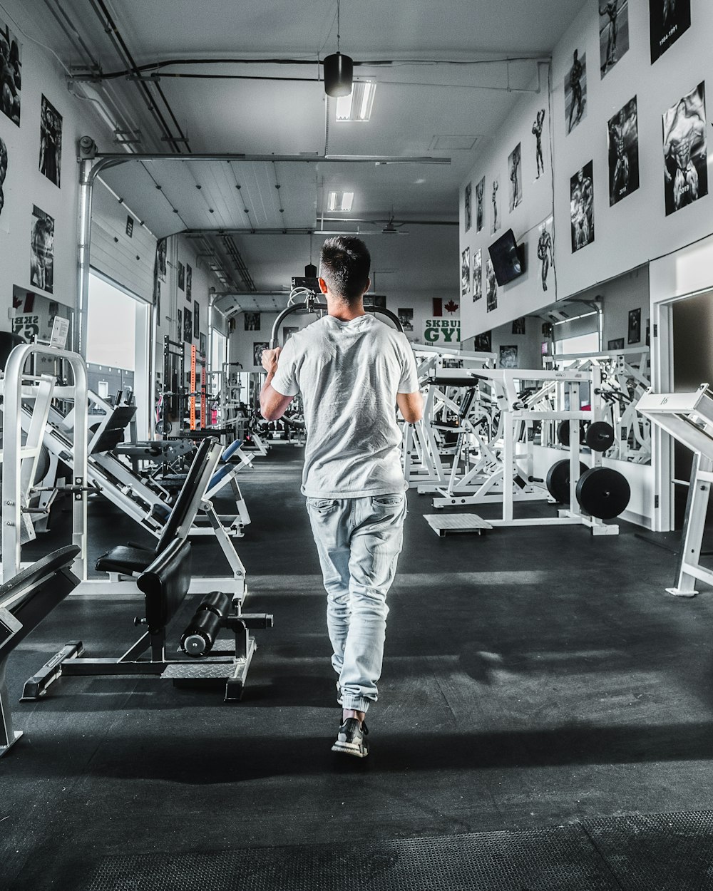 man in white and orange crew neck t-shirt and white pants standing on black floor