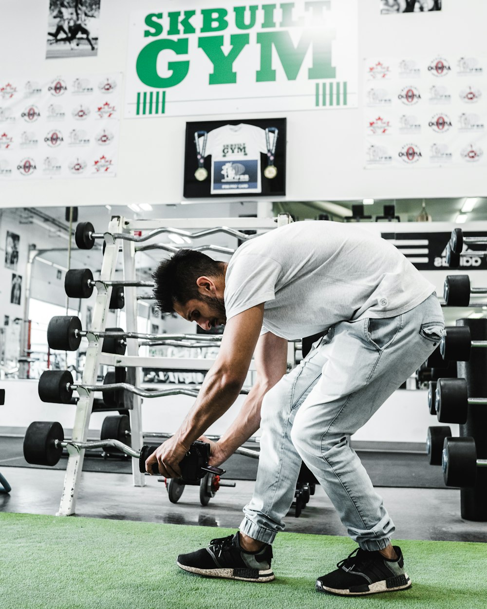 man in white t-shirt and white pants holding black and gray dumbbell
