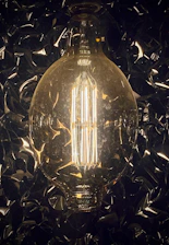 A sleek, modern LED bulb glowing warmly against a dark background with blue and yellow accents.