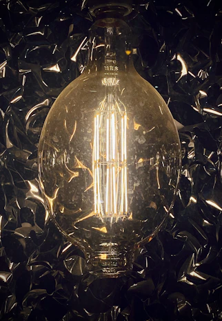 A sleek, modern LED bulb glowing warmly against a dark background with blue and yellow accents.
