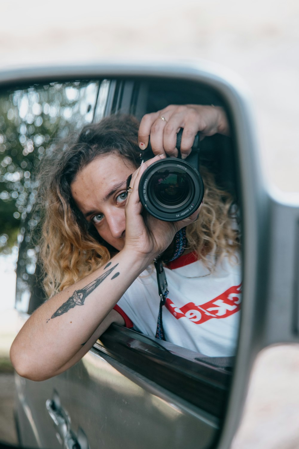 woman in white and red shirt holding black camera