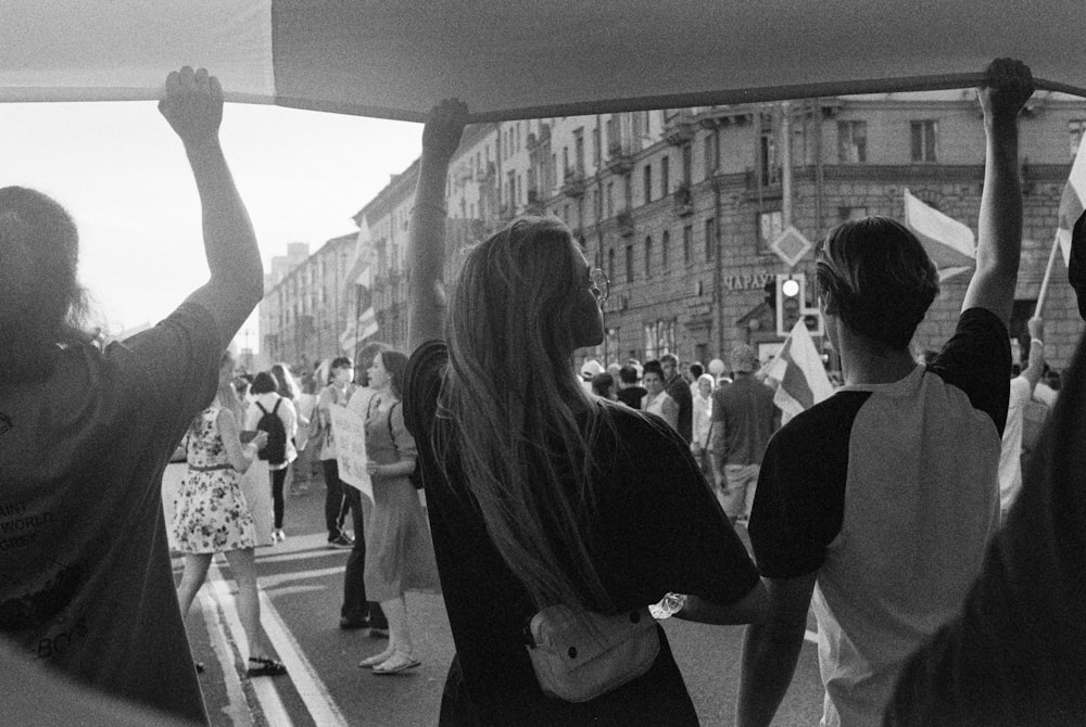 grayscale photo of woman in floral dress standing in front of people