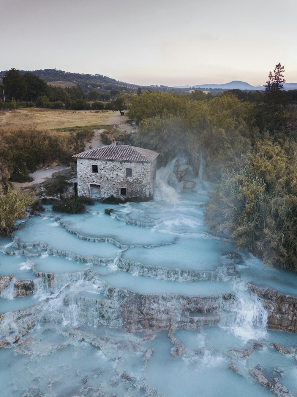 Casa de hormigón gris en un campo de hierba verde cerca del río durante el día