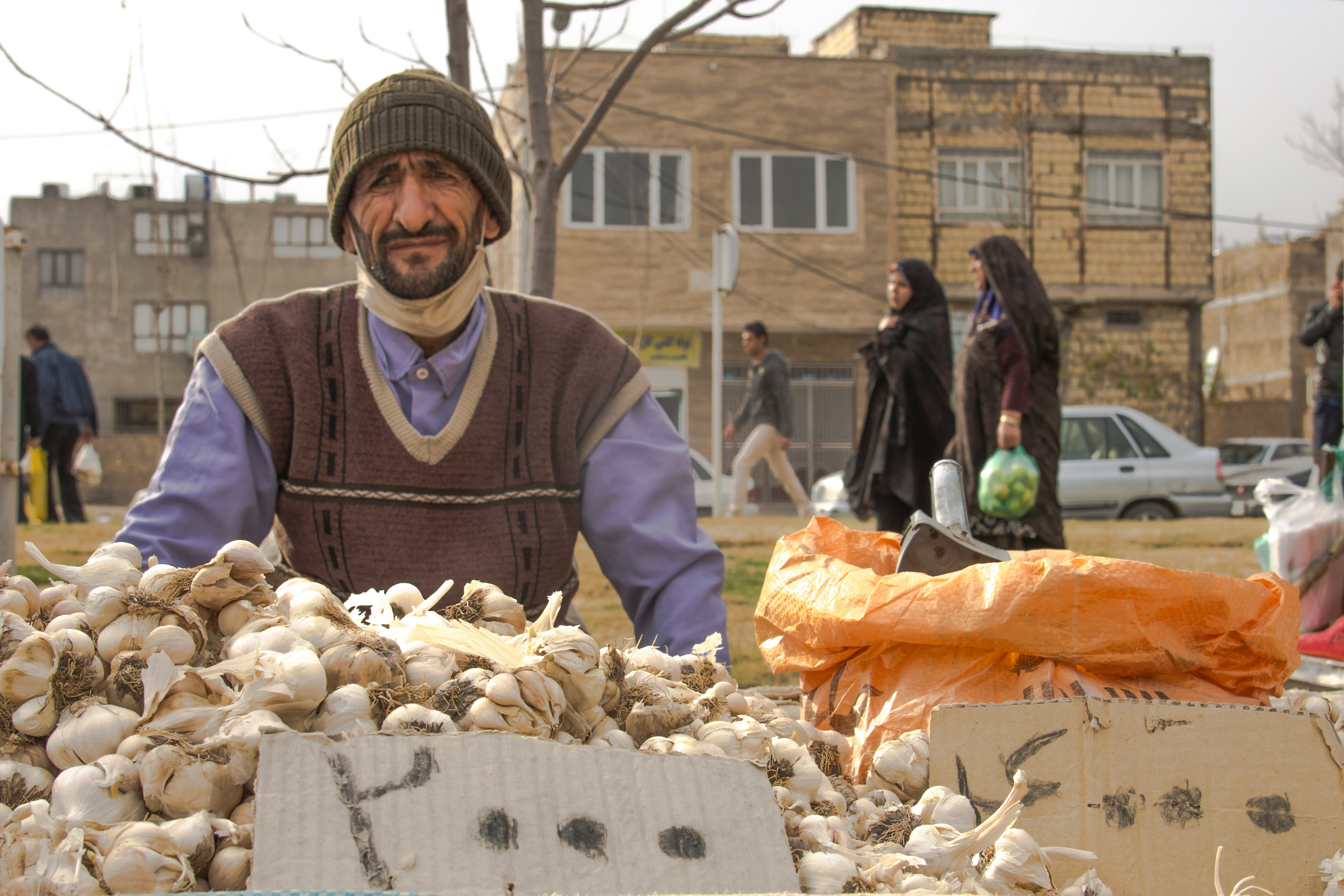 man in gray jacket standing in front of brown and white mushrooms