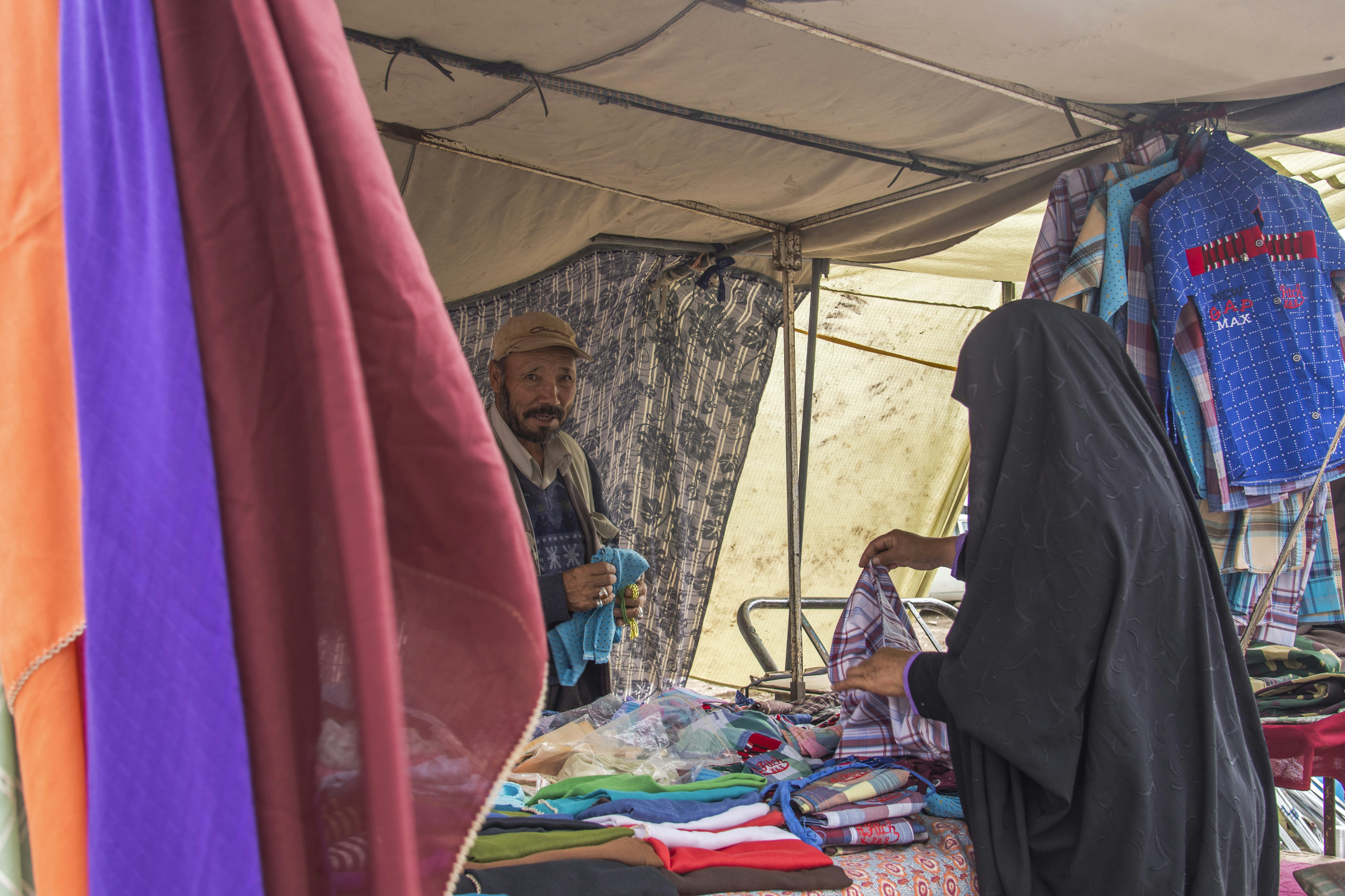 woman in black hijab sitting on blue and red textile