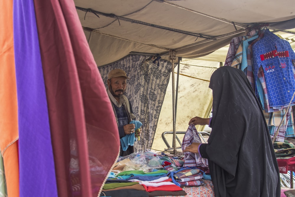 Frau im schwarzen Hijab sitzt auf blauem und rotem Textil