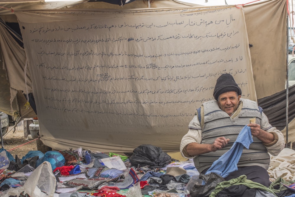 a man sitting in front of a pile of clothes