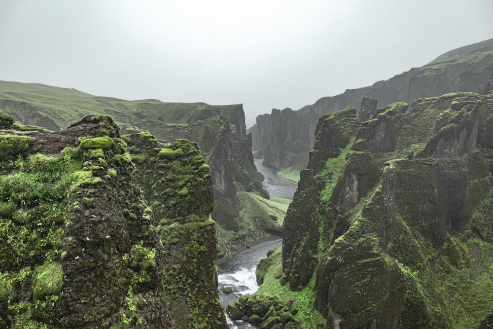 river between green mountains under white sky during daytime