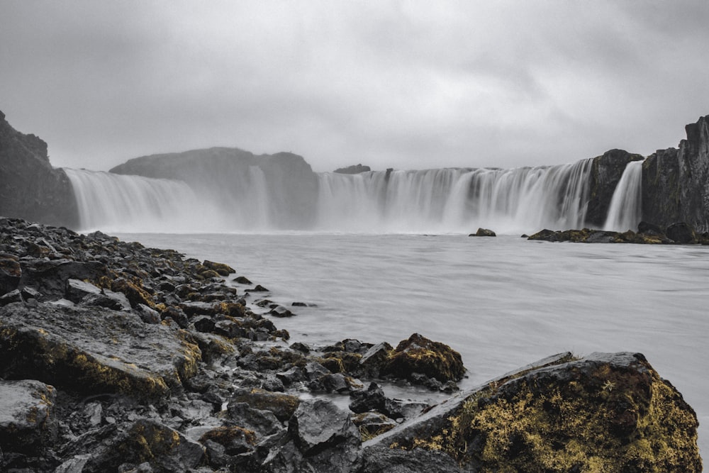 water falls on rocky shore during daytime