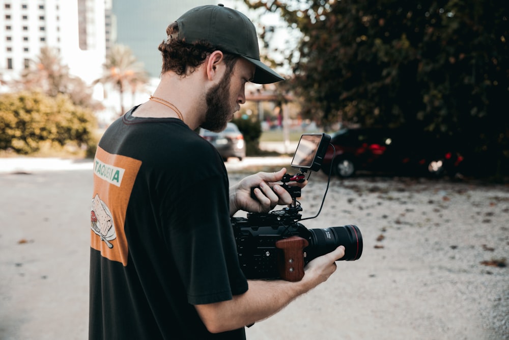 man in black shirt holding black dslr camera