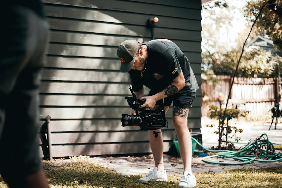 man in black t-shirt and gray shorts holding black dslr camera