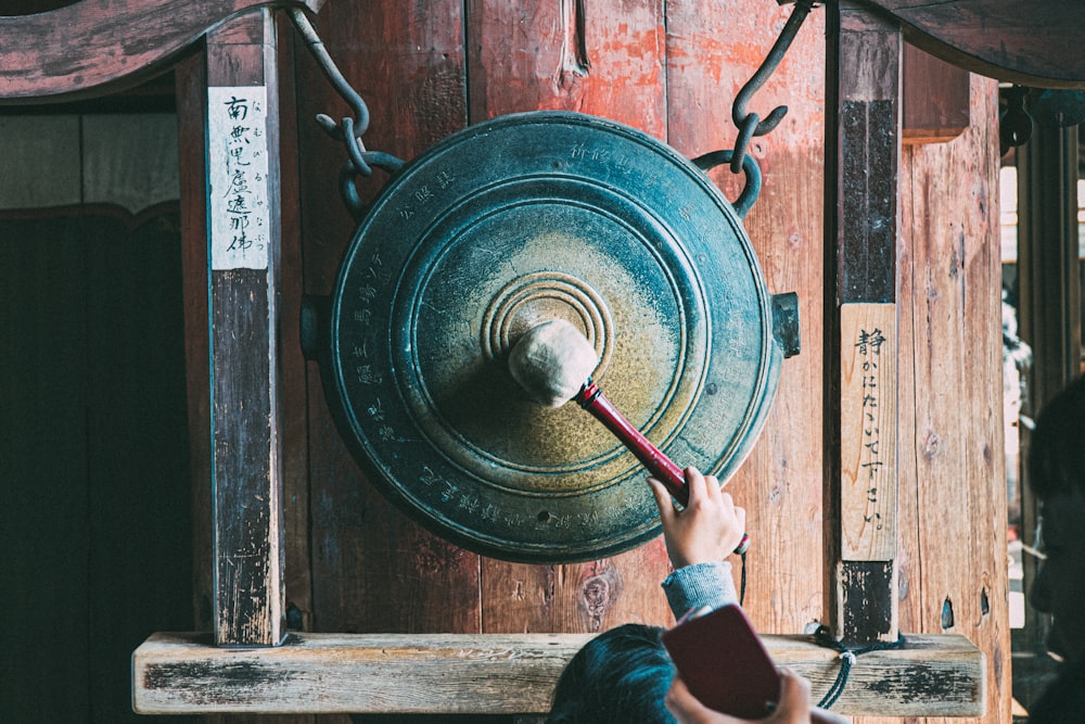 person holding round brown metal tool