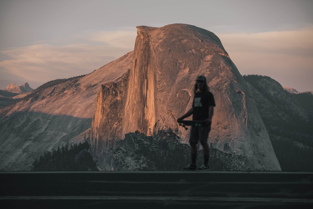 man in black jacket standing on rock formation during daytime